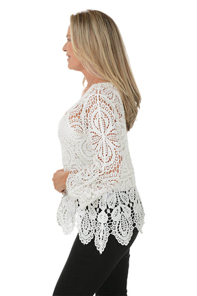 Woman wearing a white lace top on a white background. Side shot.