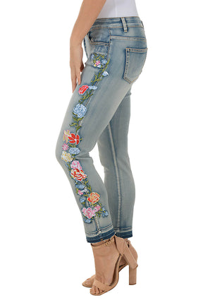 Light blue jeans with floral embroidery on a white background. Side shot.