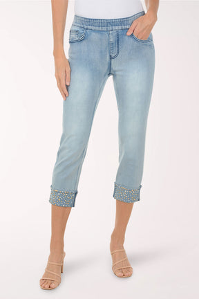 Light blue jeans with embellished cuffs worn by a person on a white background