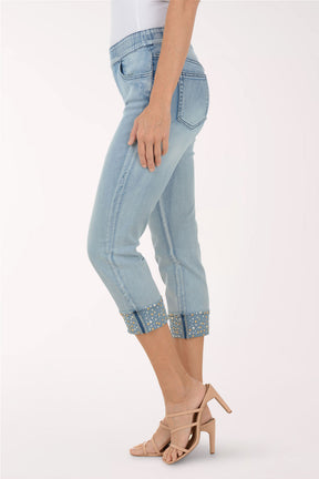 Light blue jeans with embellished cuffs worn by a person on a white background