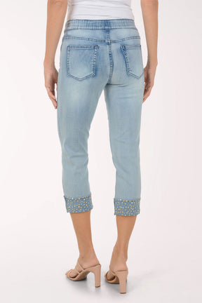Light blue jeans with embellished cuffs worn by a person on a white background