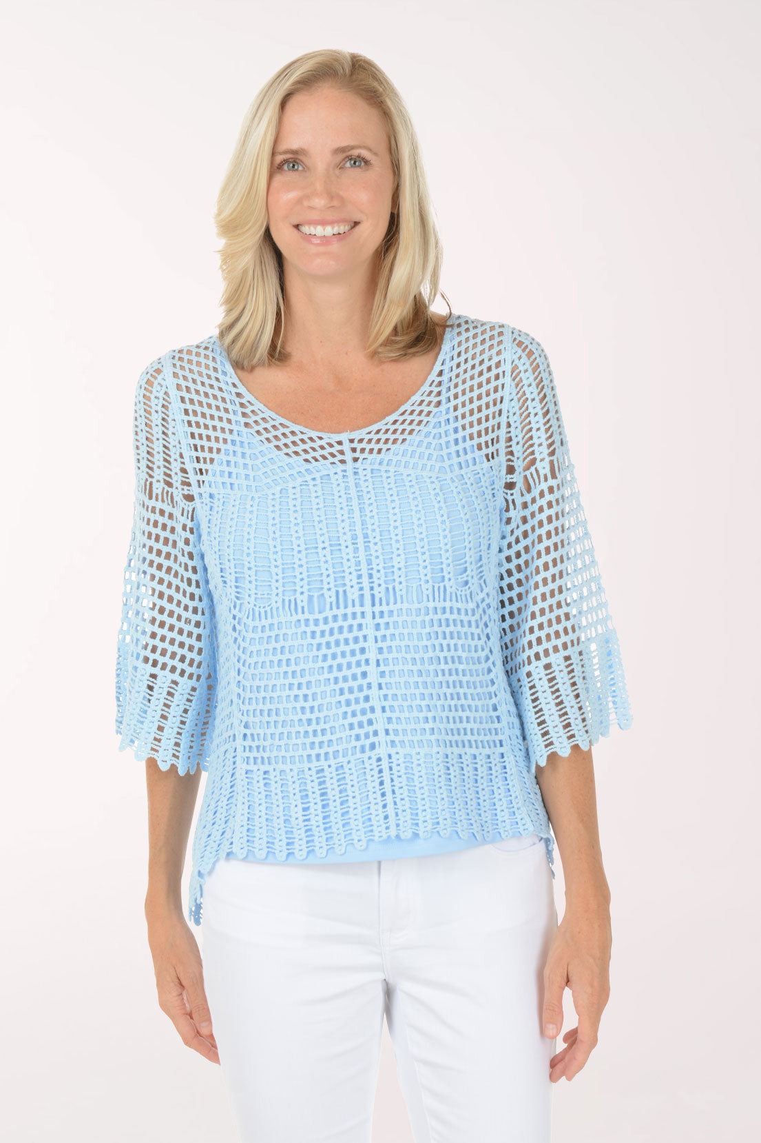 Woman wearing a white crochet top and striped pants on a white background