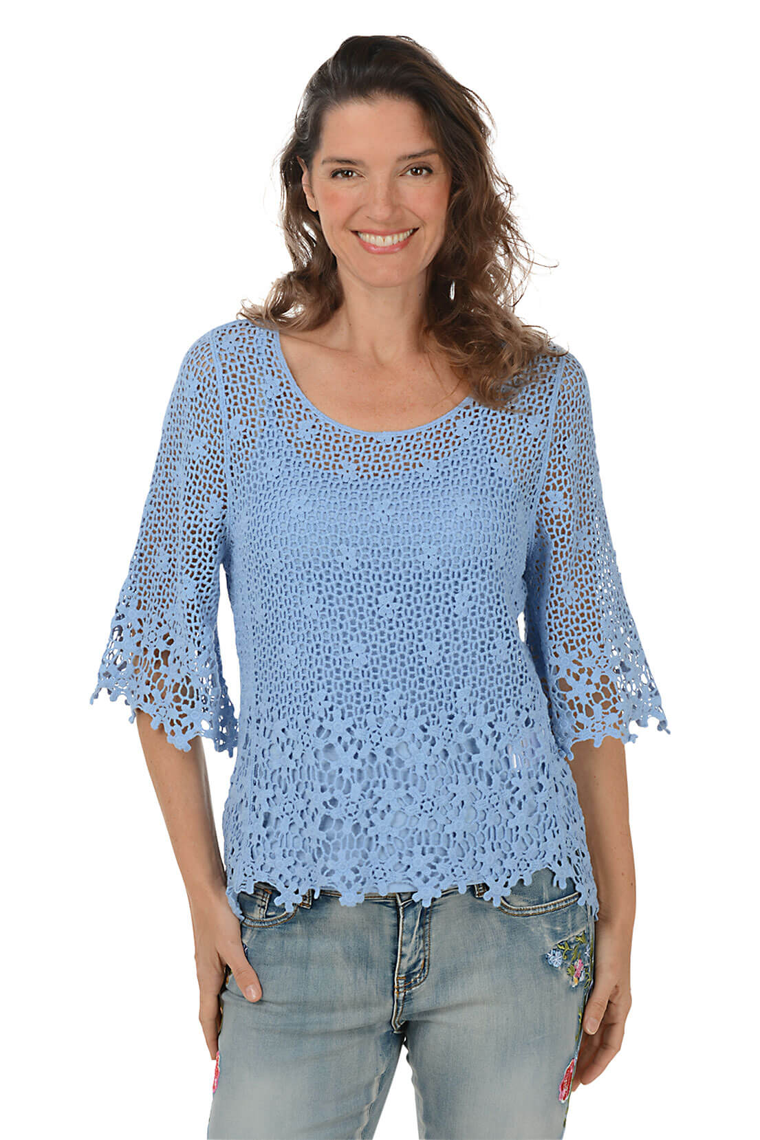 Woman wearing a blue crochet top and jeans on a white background.