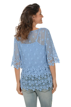 Woman wearing a blue crochet top and jeans on a white background. Back shot.