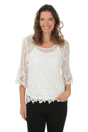 Woman wearing a white lace top with black pants on a white background.