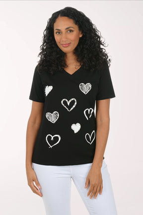 Woman wearing a black t-shirt with white heart patterns on a plain background
