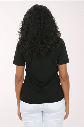 Woman wearing a black t-shirt with white heart patterns on a plain background