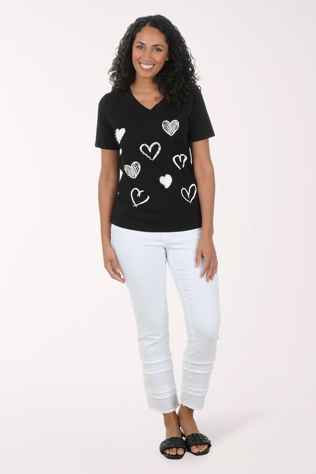 Woman wearing a black t-shirt with white heart patterns on a plain background