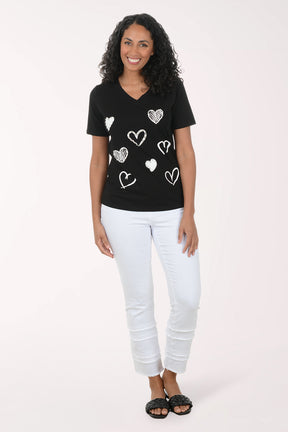 Woman wearing a black t-shirt with white heart patterns on a plain background