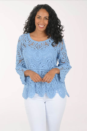Woman wearing a light blue lace top against a white background