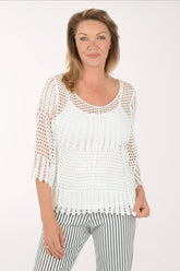 Woman wearing a white crochet top and striped pants on a white background