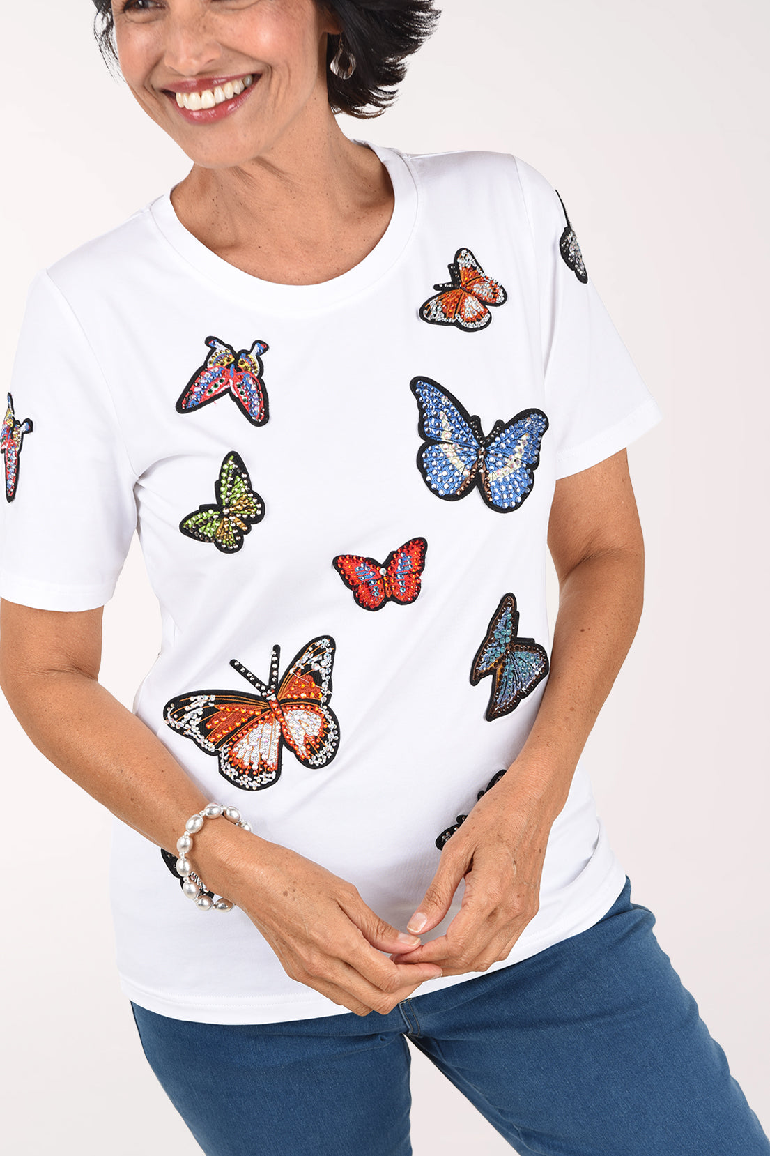 Front close-up of the white butterfly tee showing the colorful jeweled butterflies and short sleeves.