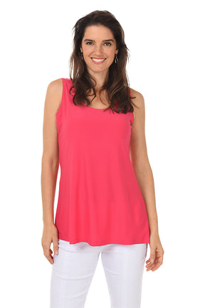 Woman wearing a pink sleeveless top and white pants on a white background