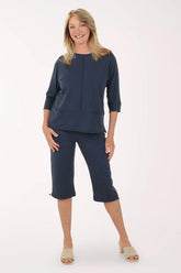 Woman wearing a navy outfit with a top and capri pants on a white background
