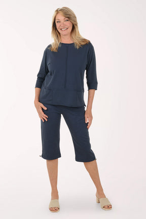 Woman wearing a navy outfit with a top and capri pants on a white background