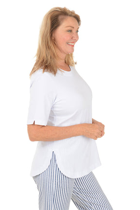 Woman wearing a white top and striped pants on a white background. Side shot.