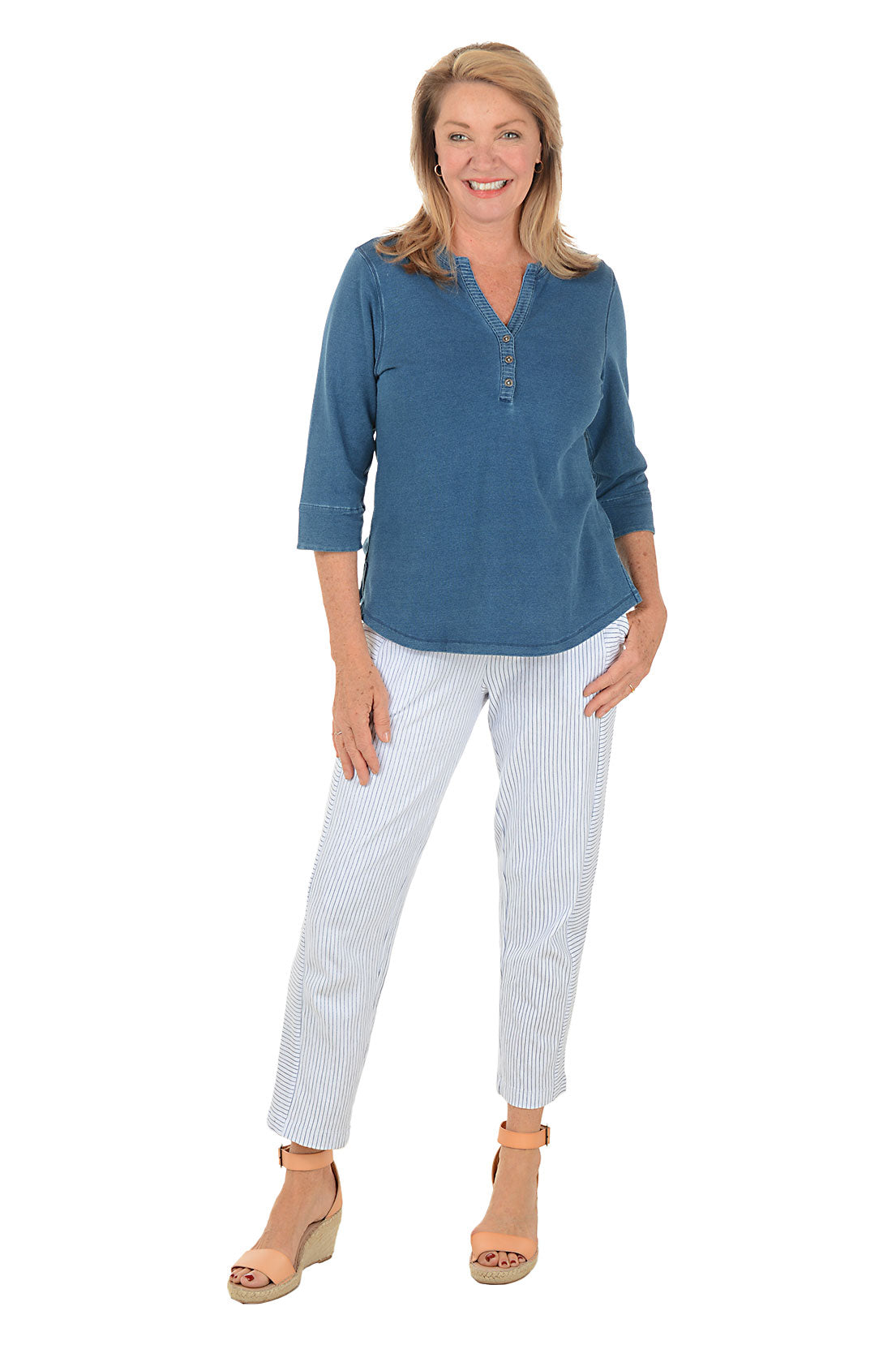 Woman wearing a blue top and white striped pants on a white background.