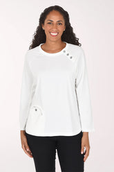 Woman wearing a white long sleeve top with three button embellishment