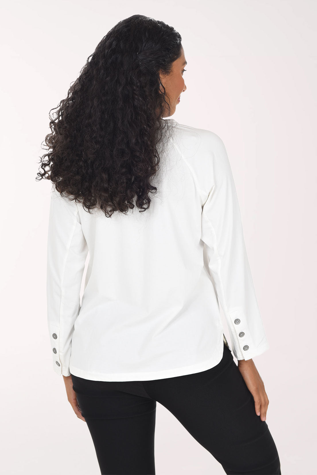 Woman wearing a white long sleeve top with three button embellishment