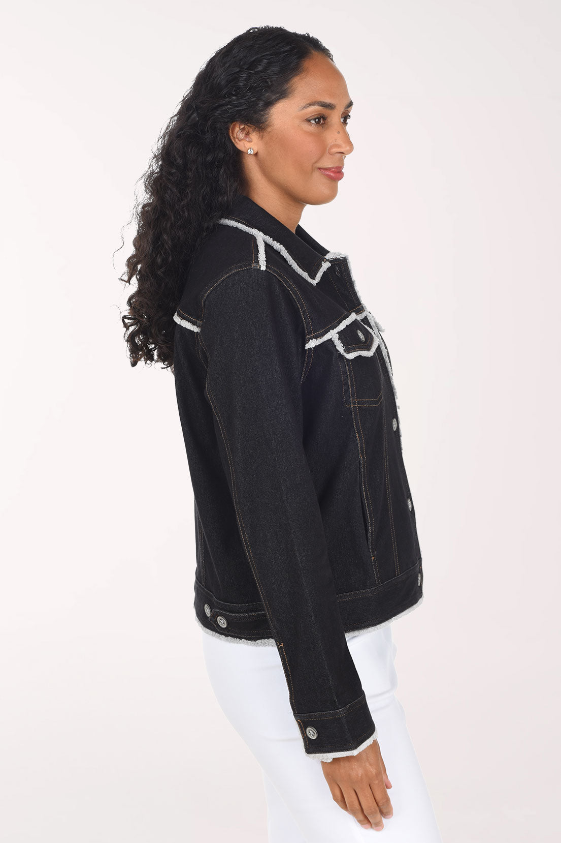 Woman wearing a black denim button down jacket with contrast stitching and fringing
