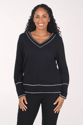 Woman wearing a black long sleeve v-neck top with white contrast stitching
