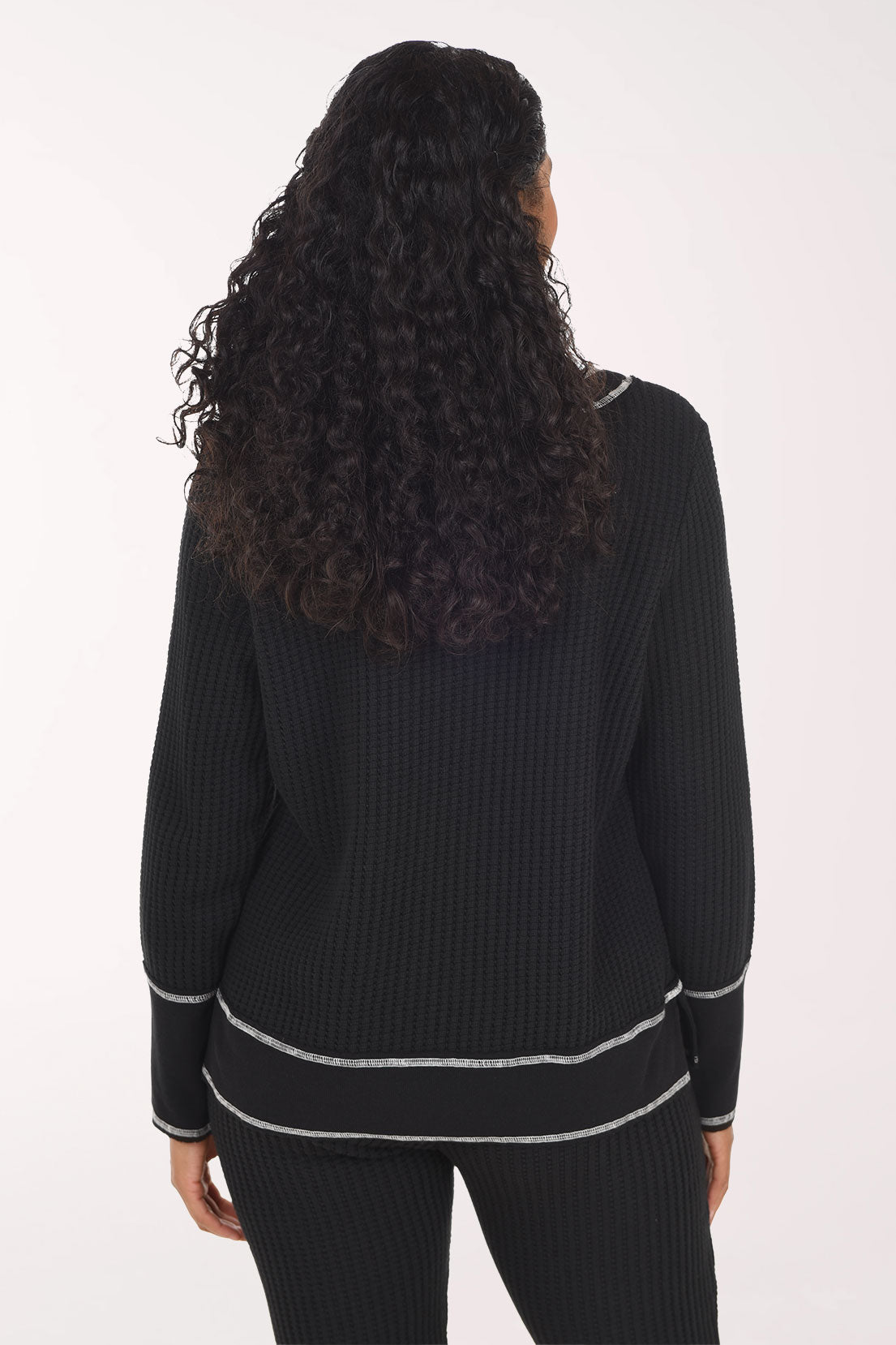 Woman wearing a black long sleeve v-neck top with white contrast stitching