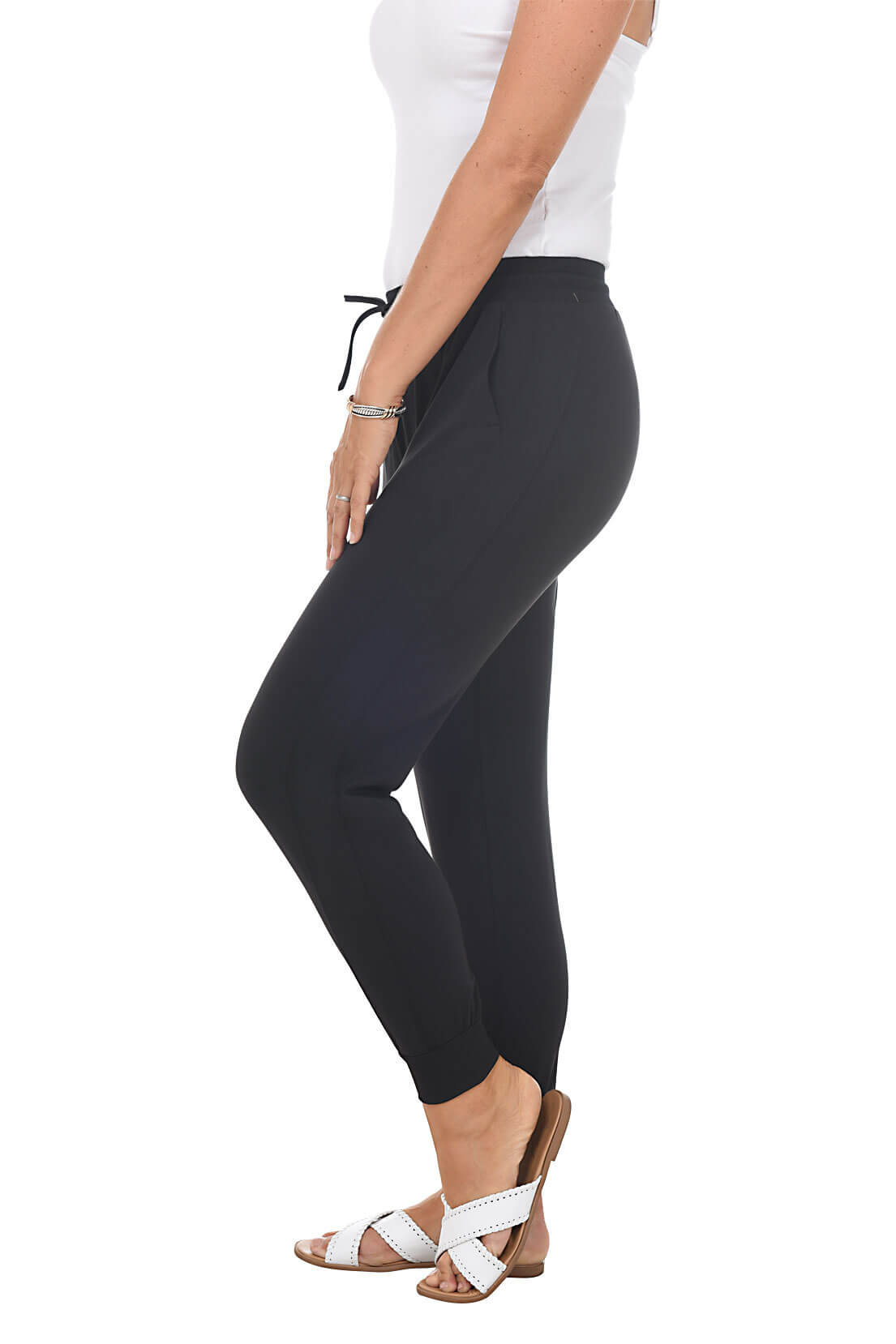 Person wearing black joggers and white top on a white background. Side shot.