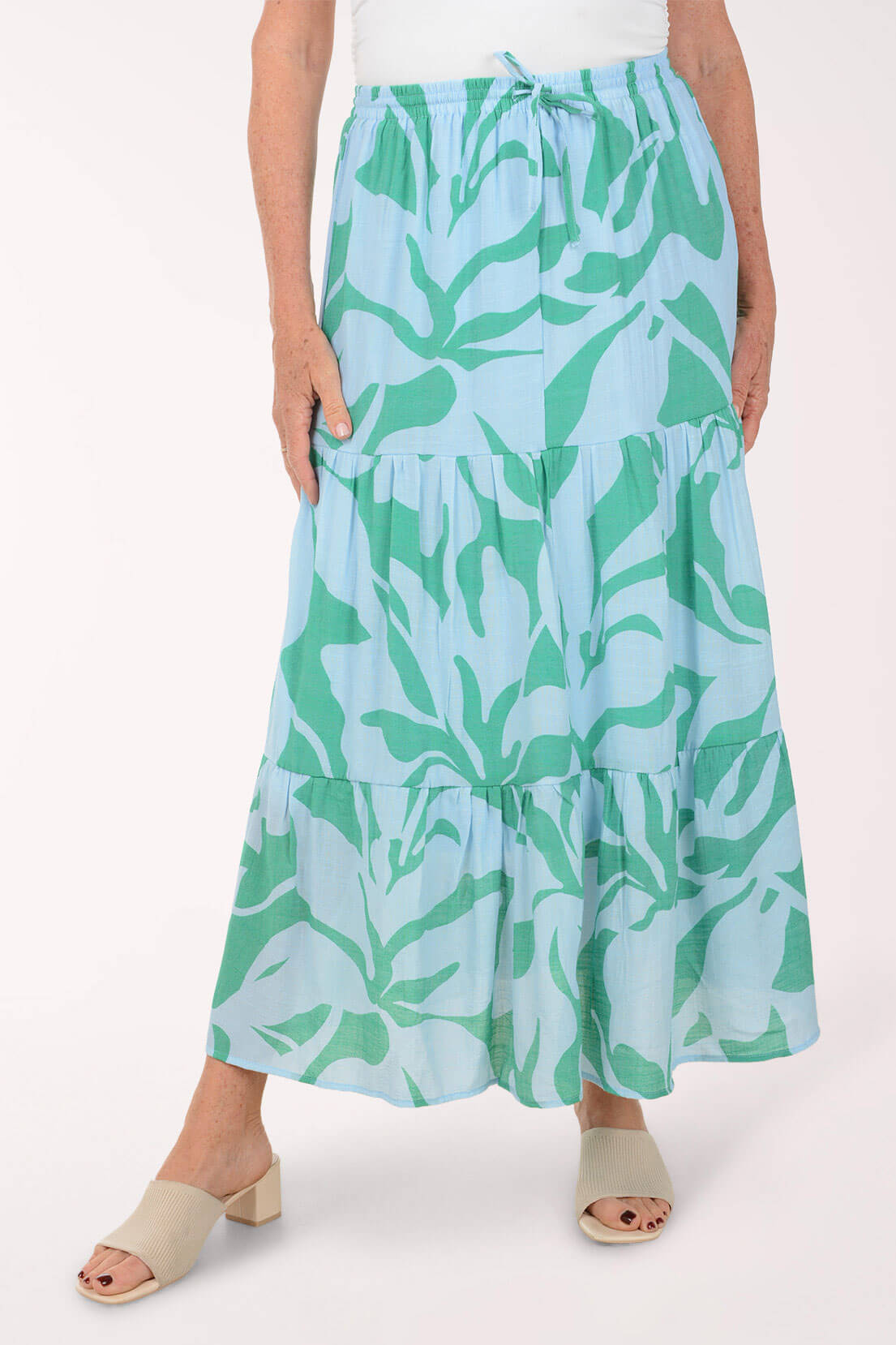 Person wearing a blue and green leaf-patterned skirt on a white background