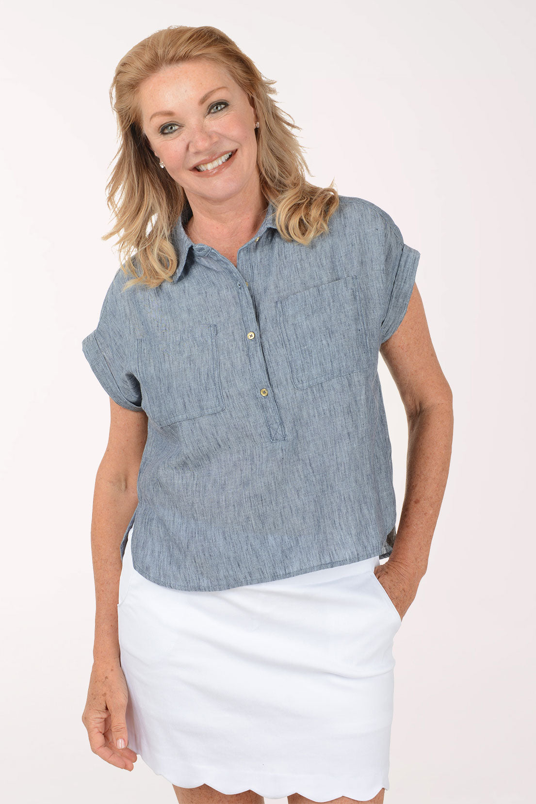 Woman wearing a blue cap sleeve shirt and white skirt on a white background