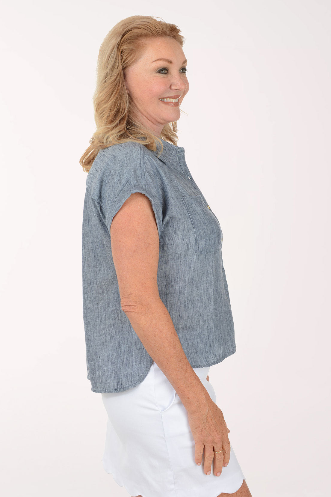 Woman wearing a blue cap sleeve shirt and white skirt on a white background