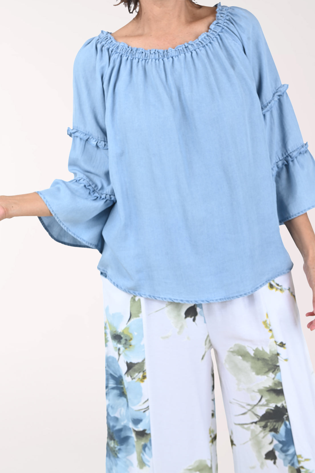 Woman wearing a light blue blouse with ruffled sleeves on a white background