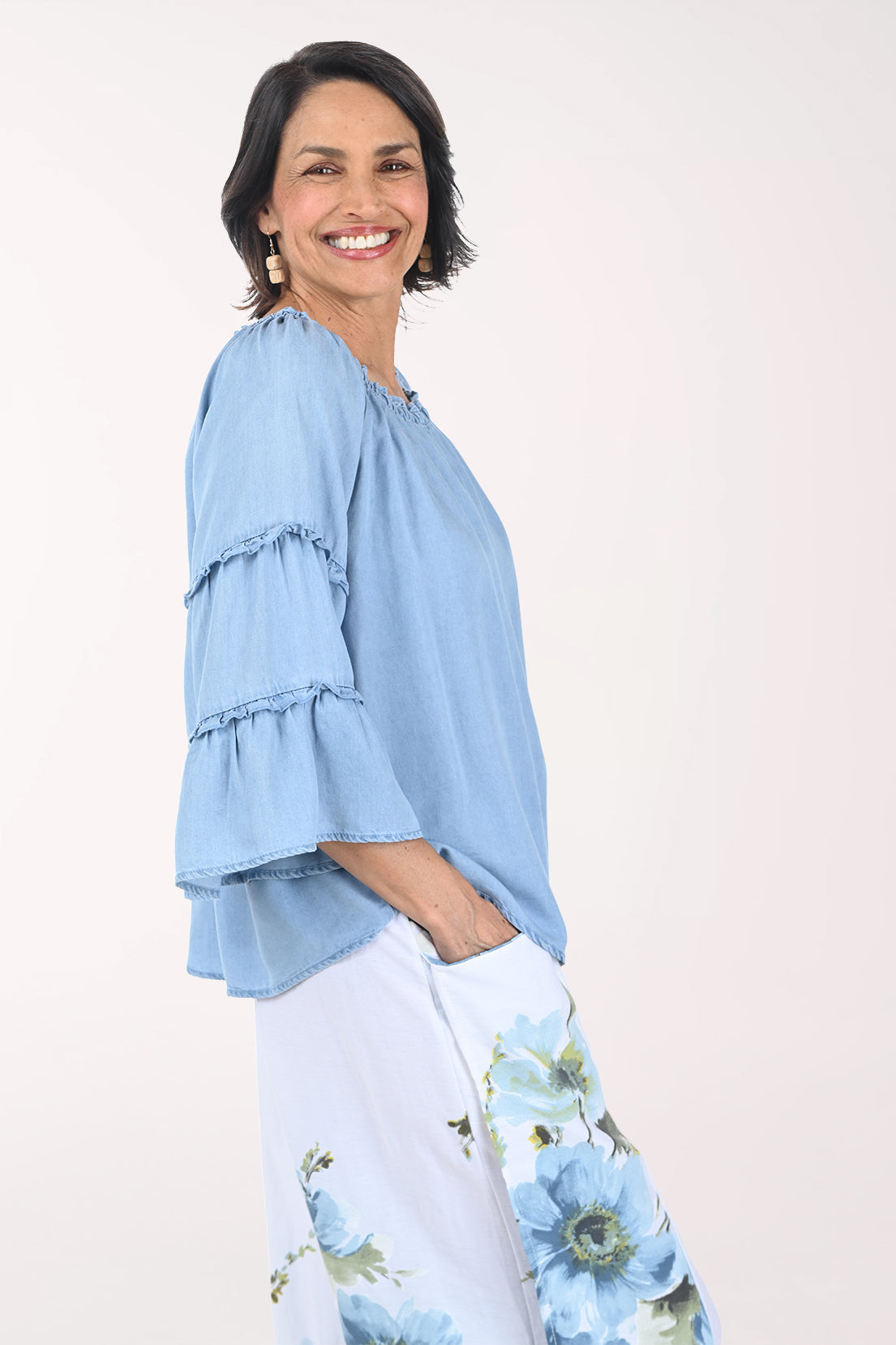 Woman wearing a light blue blouse with ruffled sleeves on a white background