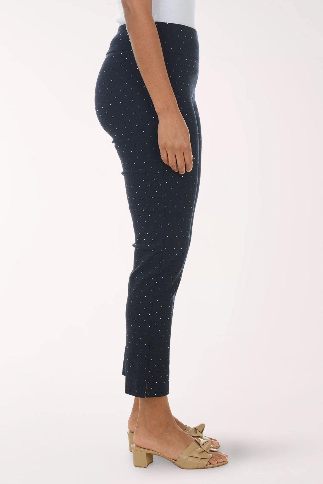 Navy blue pants with white polka dots worn by a person on a white background