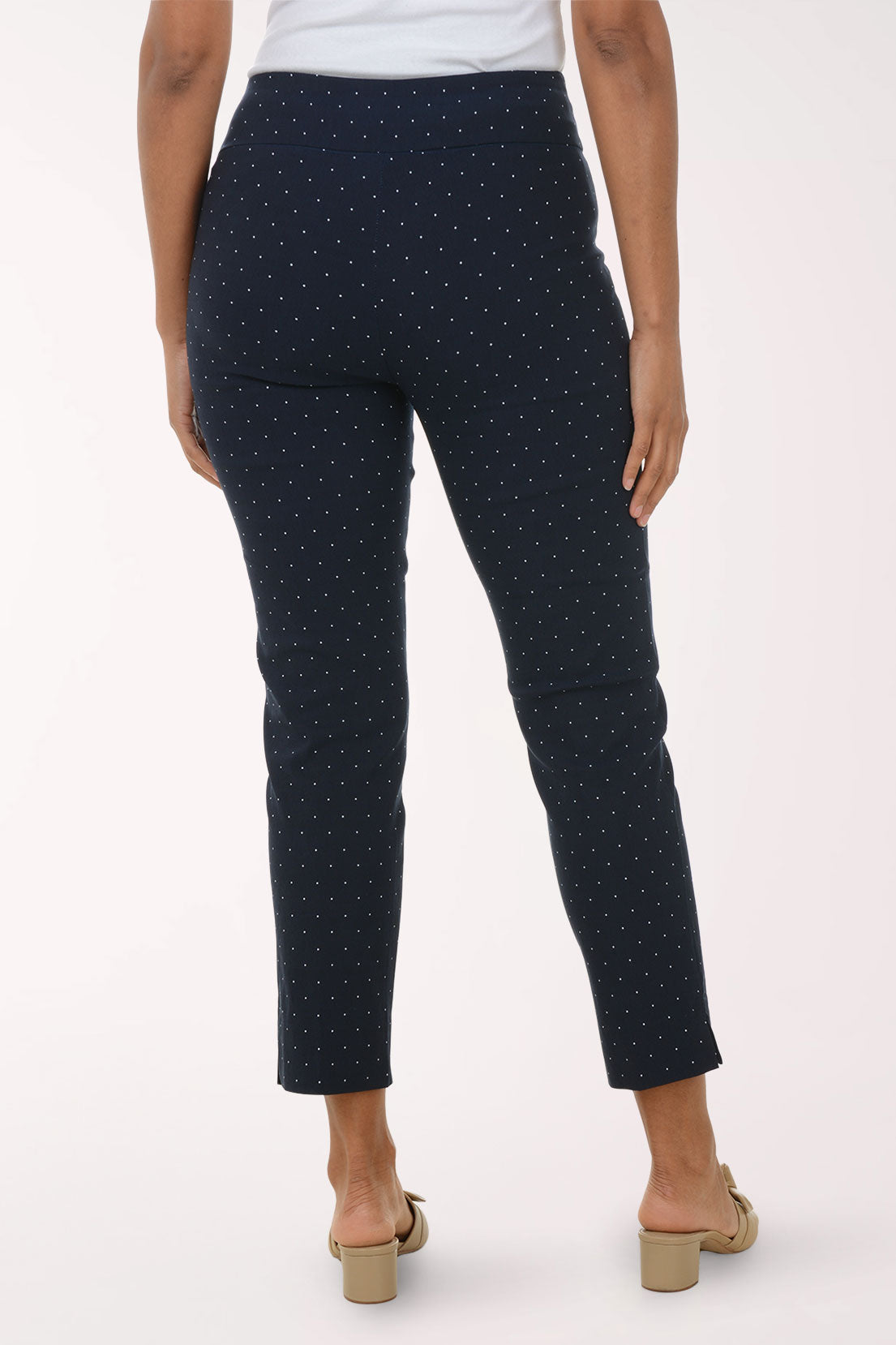 Navy blue pants with white polka dots worn by a person on a white background