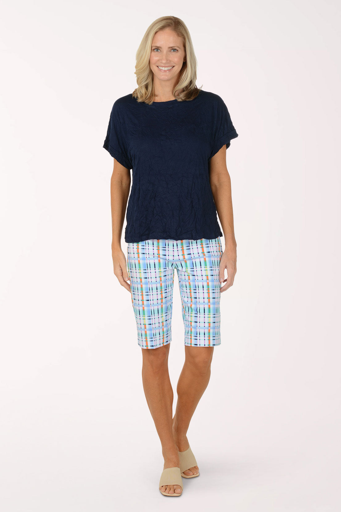 Woman wearing a navy top and plaid shorts on a white background