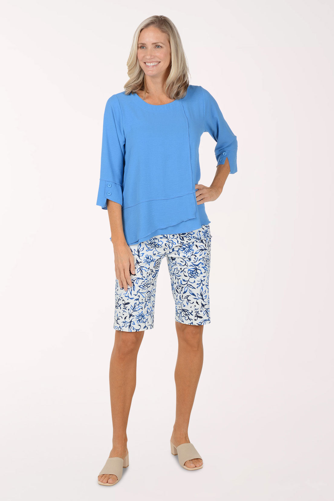 Woman wearing a blue top and floral shorts on a white background