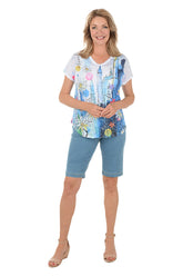 Woman wearing a colorful top and blue shorts on a white background