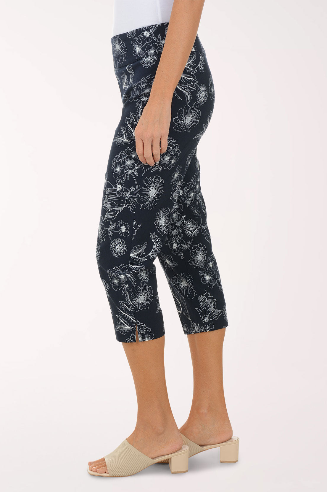 Person wearing navy capri pants with white floral pattern on a white background