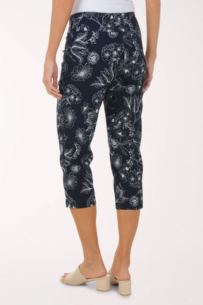 Person wearing navy capri pants with white floral pattern on a white background