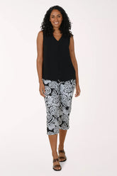 Woman wearing a black sleeveless top and patterned capri pants on a white background