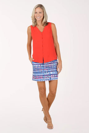 Woman wearing a red sleeveless top and patterned shorts on a white background