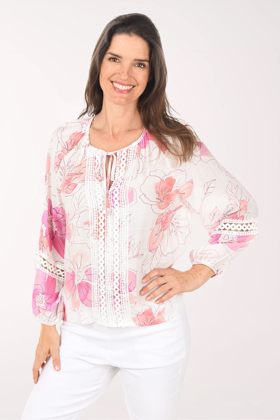 Woman wearing a white blouse with pink floral patterns on a white background