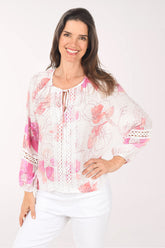 Woman wearing a white blouse with pink floral patterns on a white background