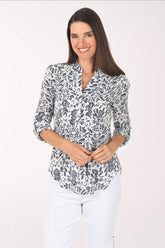 Woman wearing a patterned blouse and white pants on a white background