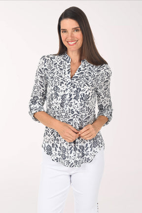 Woman wearing a patterned blouse and white pants on a white background