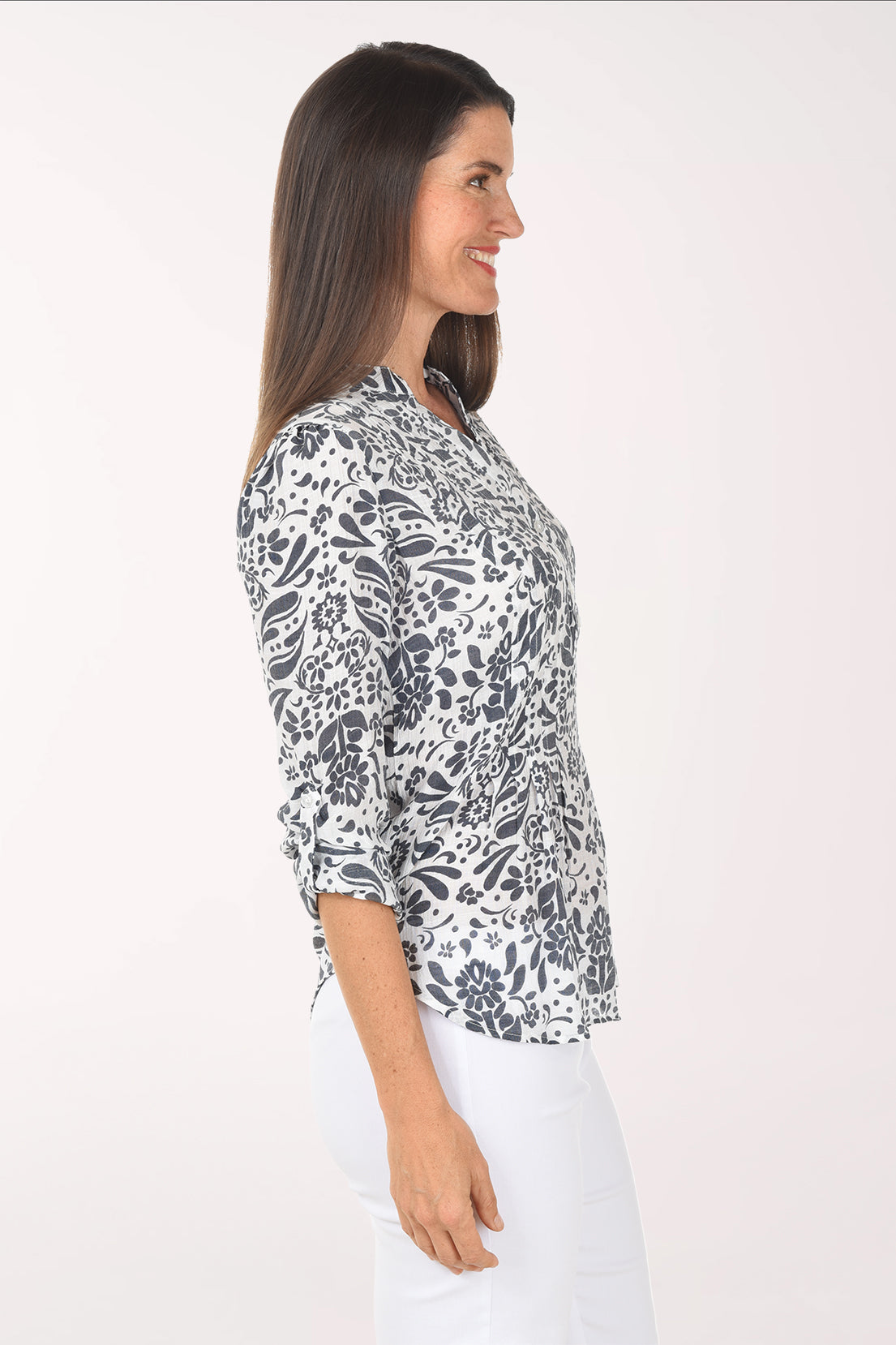 Woman wearing a patterned blouse and white pants on a white background