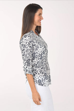 Woman wearing a patterned blouse and white pants on a white background