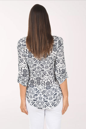 Woman wearing a patterned blouse and white pants on a white background