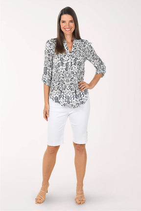 Woman wearing a patterned blouse and white pants on a white background
