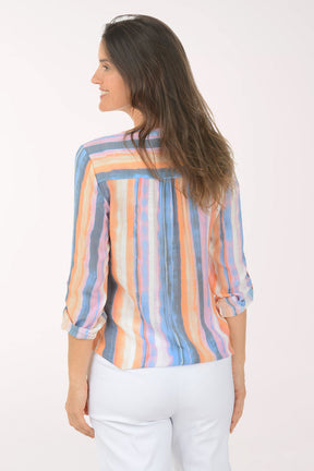 Woman wearing a colorful striped blouse and white pants on a white background
